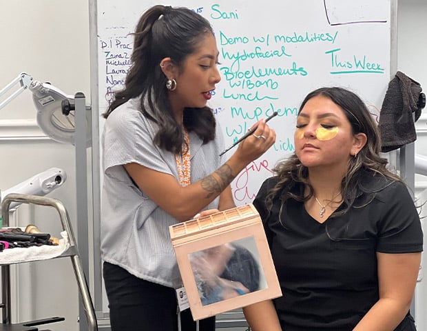 Cosmotology Cosmotology Program Training - a woman applying makeup on a woman's face