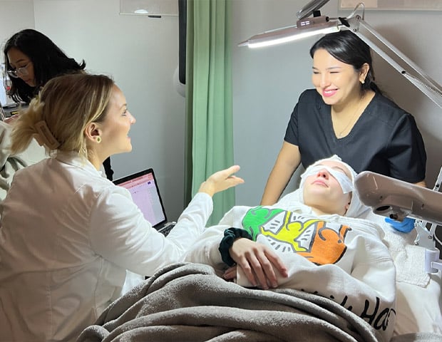 Esthetics Esthetics Program Training a woman looking at a patient lying in a bed with a lamp
