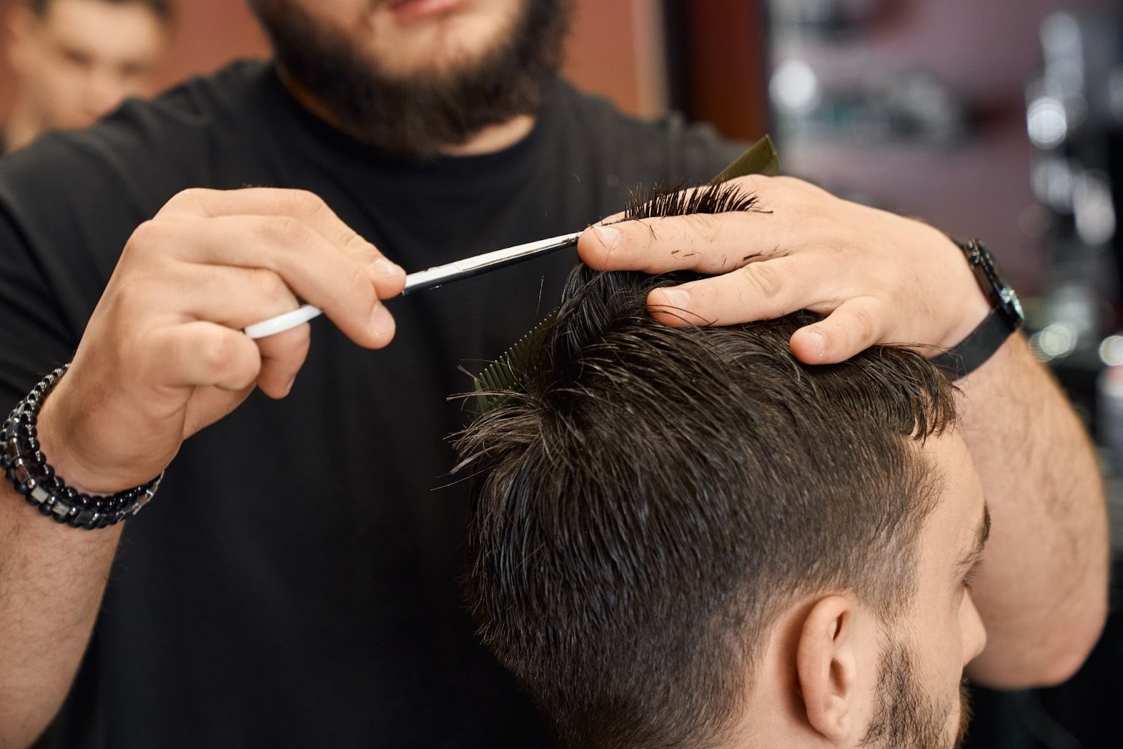 Barber using scissors and comb to cut a client’s hair in a professional barbershop
