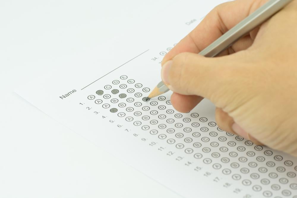 Close-up of hand filling out a multiple-choice answer sheet during an exam