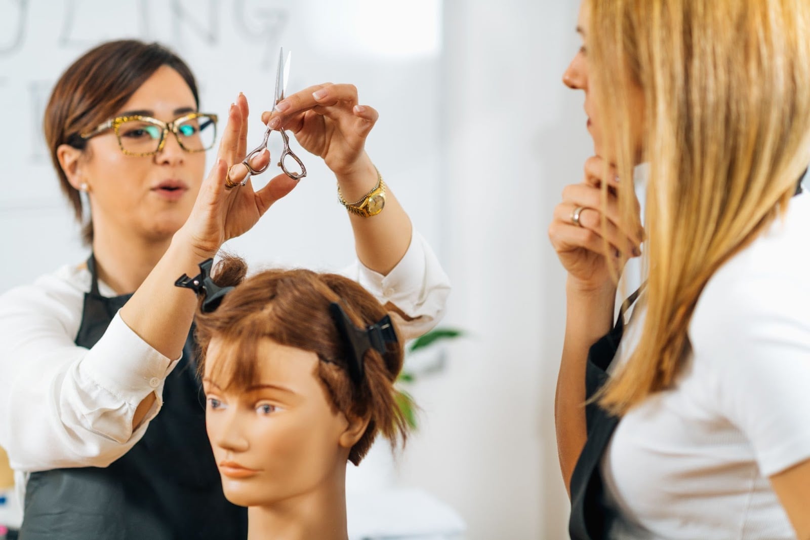 How Long Is Cosmetology School in Illinois? 2 Cosmetology instructor demonstrating haircut technique on mannequin during hands-on training session