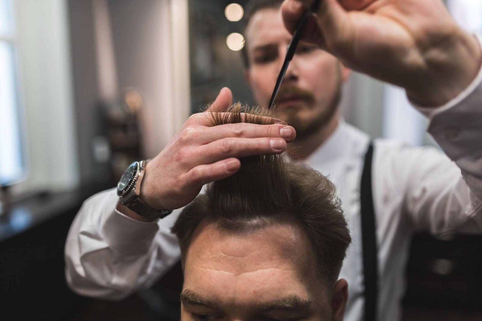 Barber styling a client’s hair with a comb and scissors in a professional barbershop