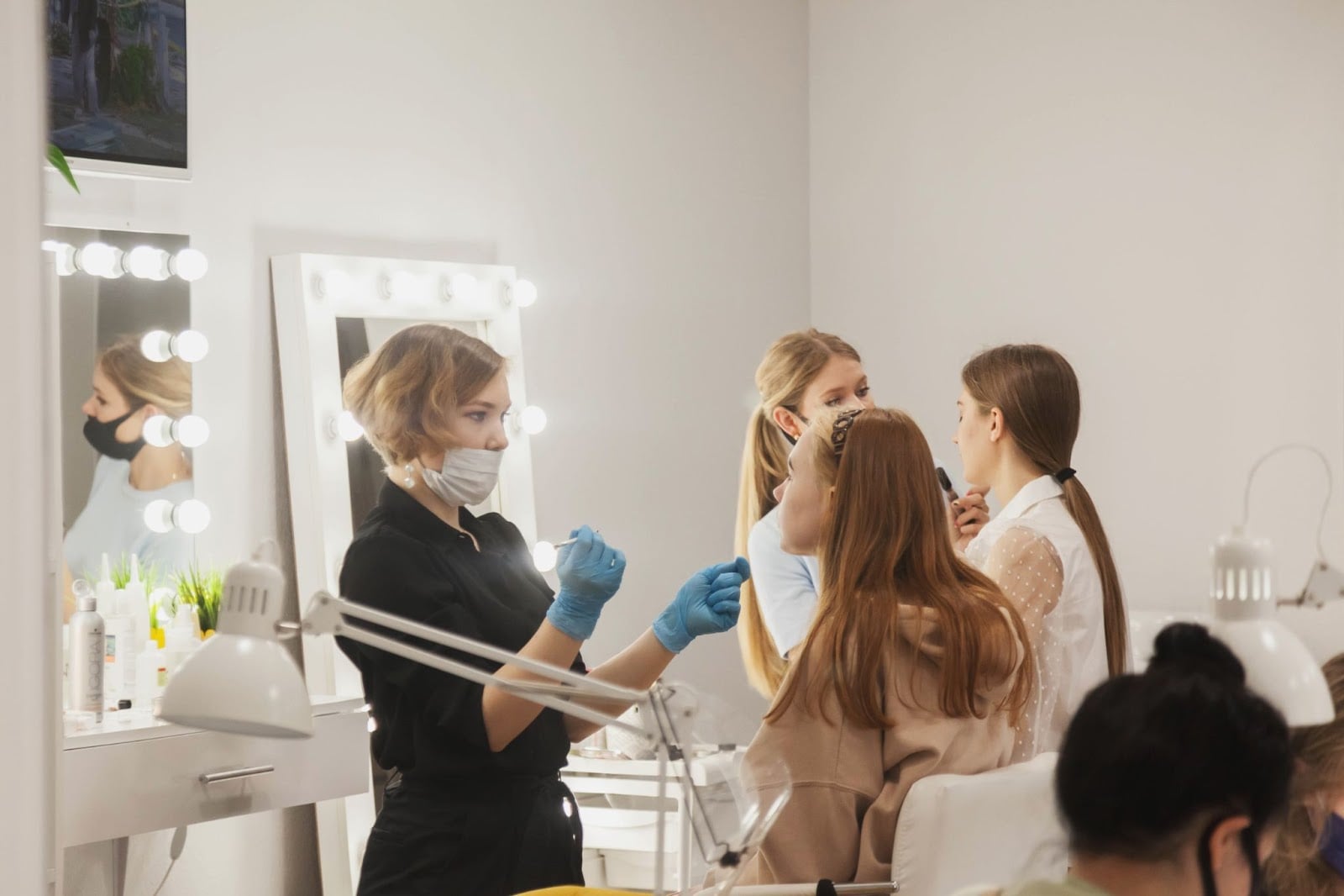 Cosmetology students practicing makeup and skincare techniques in a classroom.


