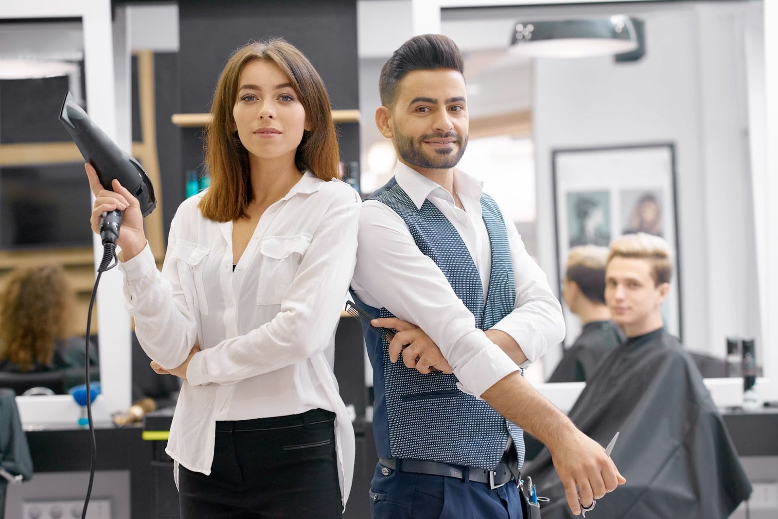Professional barber and hairdresser team ready for clients in a contemporary barbershop.