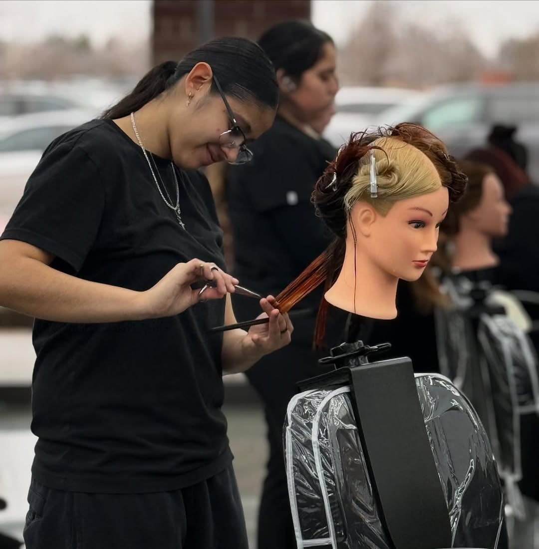 How to Choose a Beauty School: Making The Right Decision 6 Cosmetology student practicing haircutting techniques on a mannequin head during beauty school training.