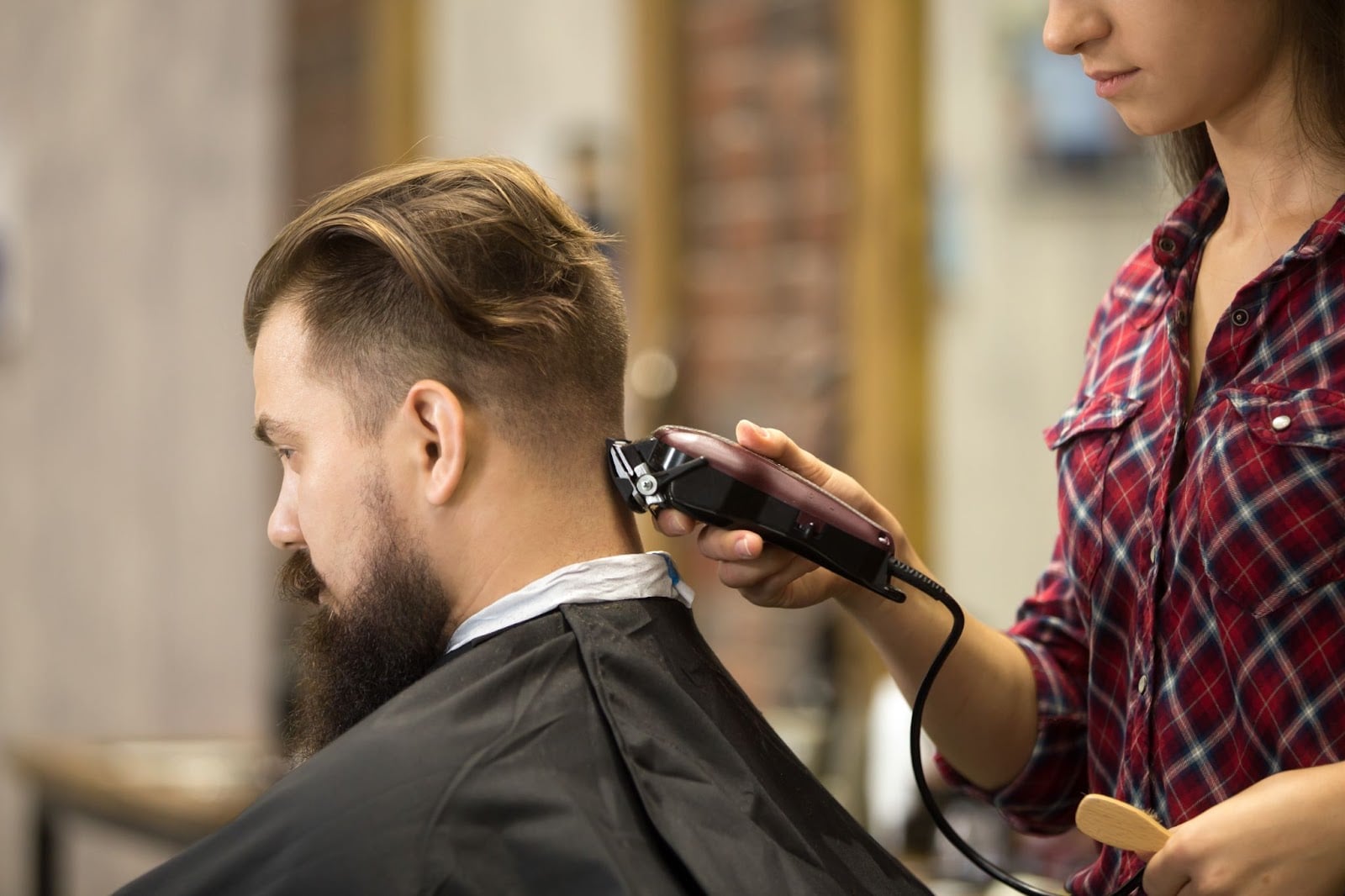 Barber student using clippers to create a fade haircut on a male client at  Academy