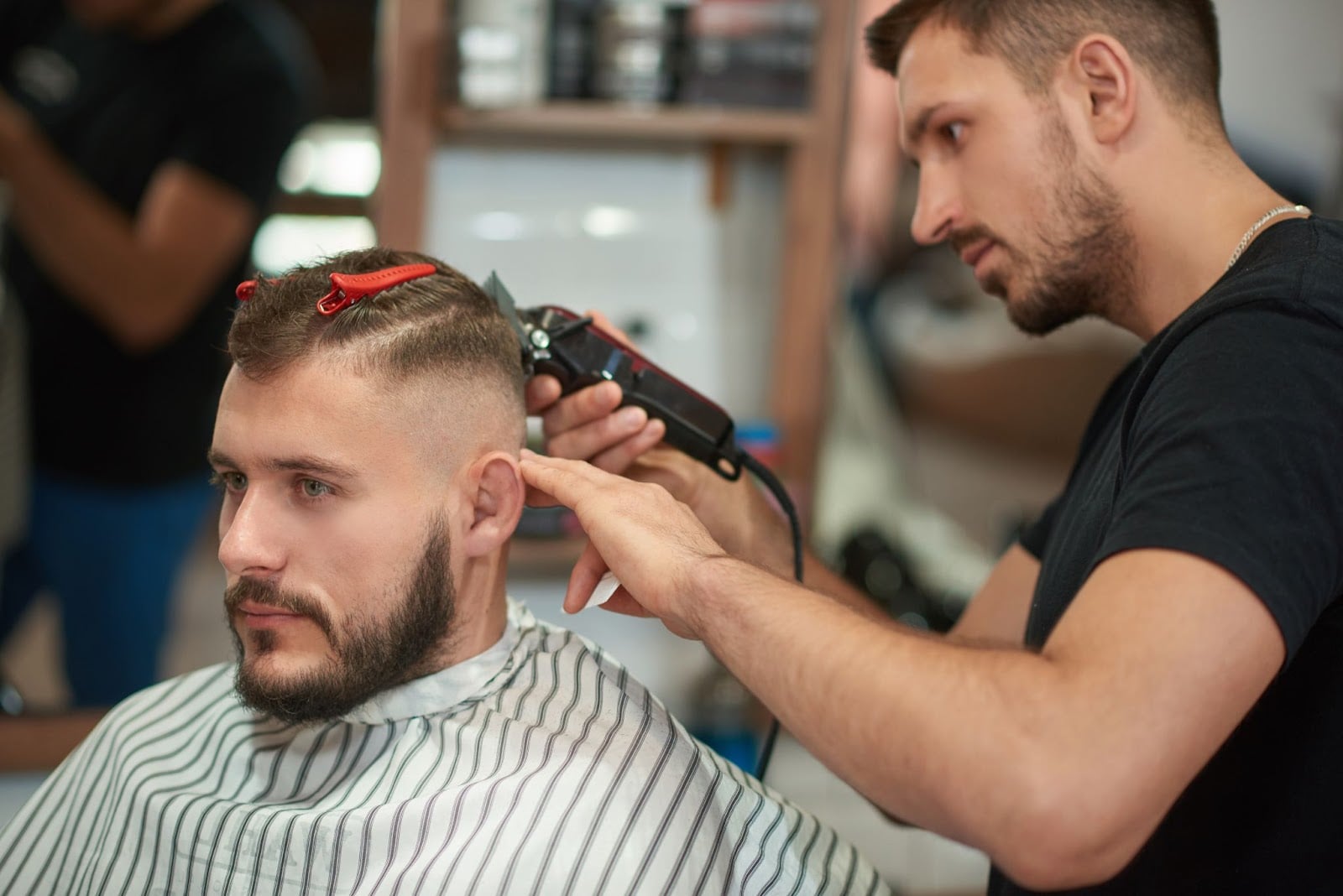 Barber giving a modern fade haircut to a male client in a professional barbershop
