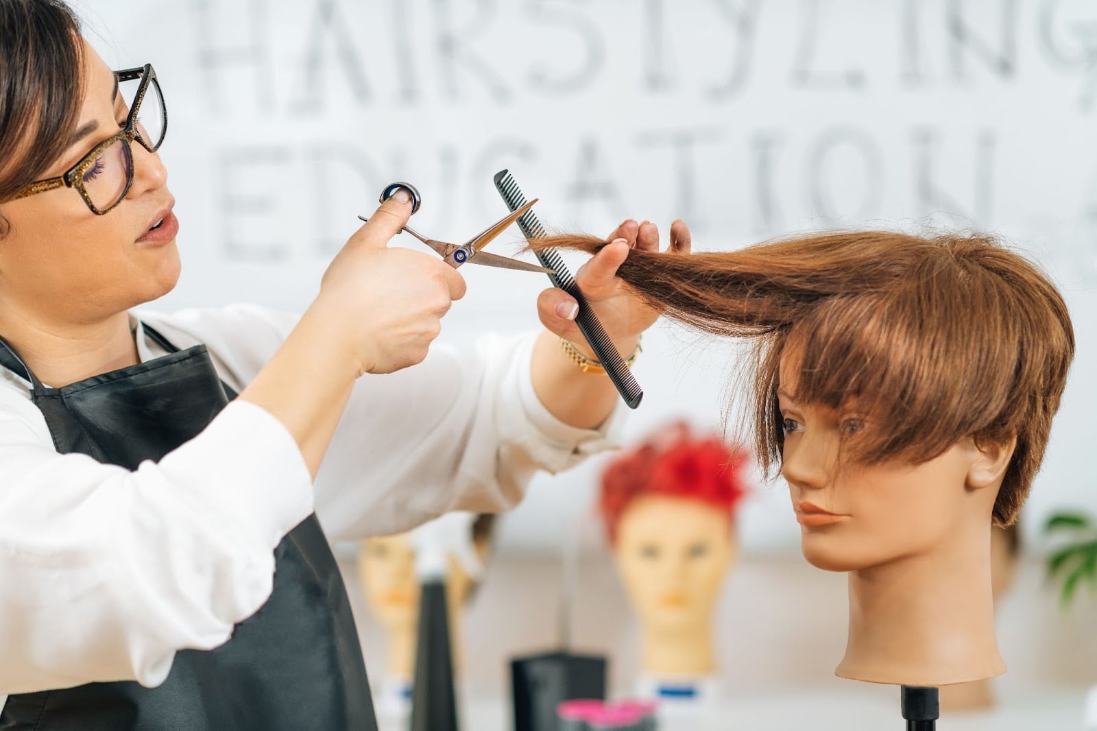 Cosmetology student practicing haircutting techniques on a mannequin at Cosmetology & Spa Academy.