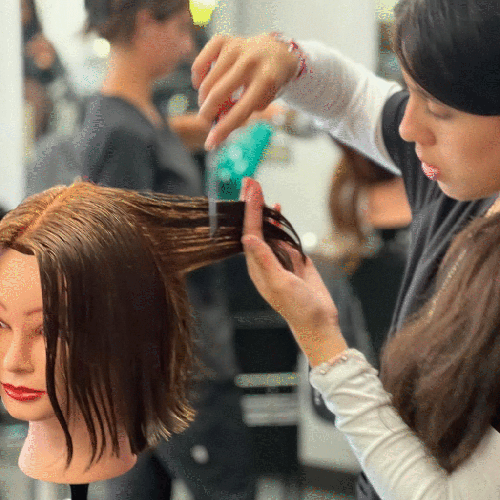 Cosmetologist vs. Esthetician vs. Barber: Choosing the Right Beauty Career Path 8 Beauty school student practicing haircutting techniques on mannequin head