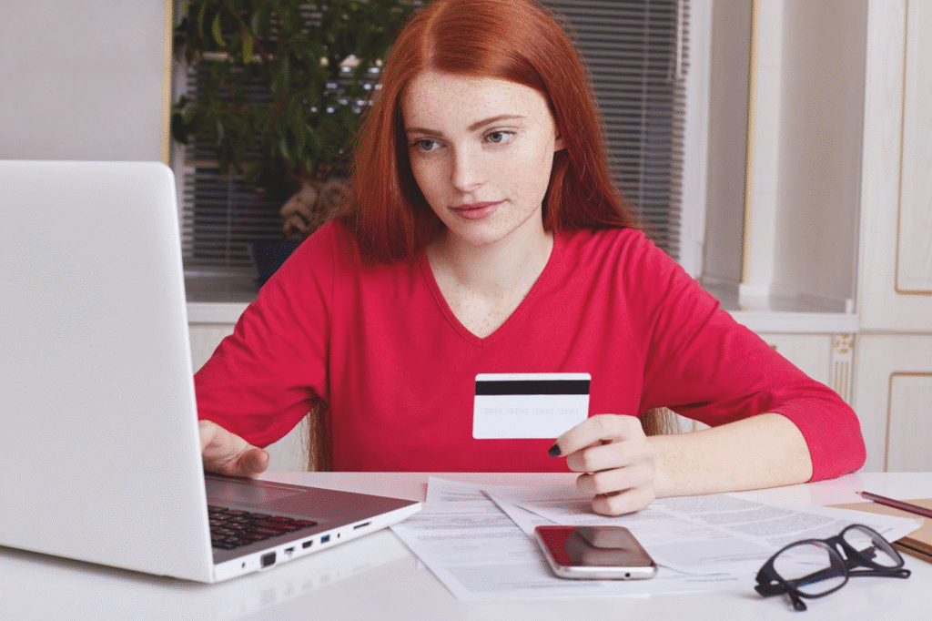 Young woman researching how to pay for beauty school online with a laptop and credit card.
