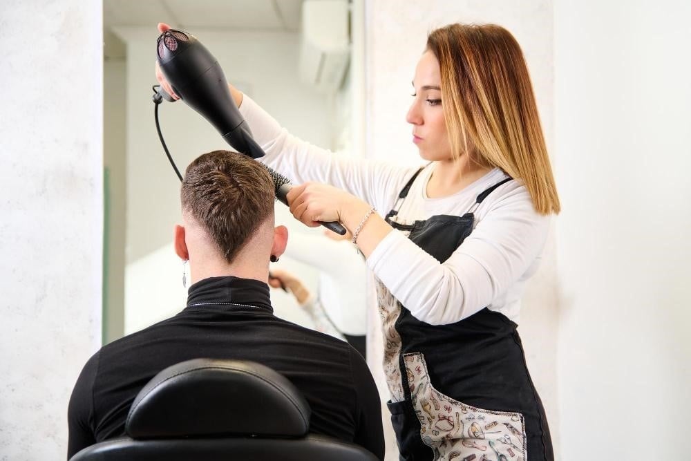 The Top Eight Personality Traits of Successful Hairstylists 2 Hair school student styling a male client's hair.