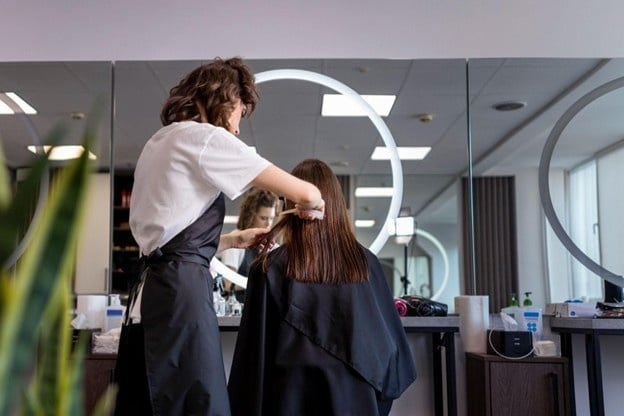 Benefits of Becoming a Cosmetologist: More Than Just a Job 4 Student at a cosmetology school in Illinois practicing different hair cutting techniques on a client