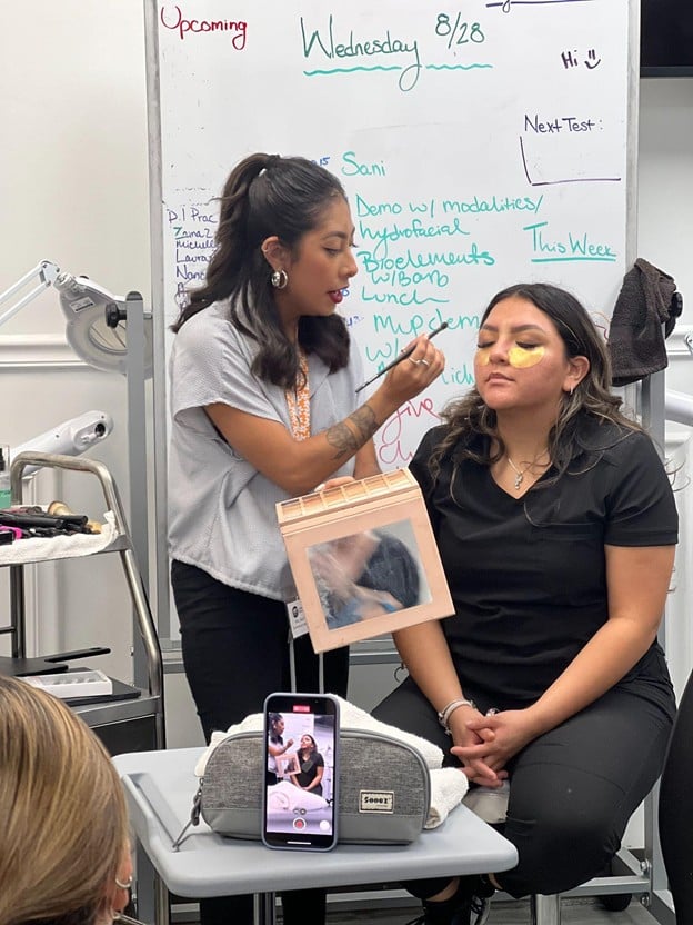 Makeup artistry student practicing professional makeup application on a model during hands-on training at Cosmetology & Spa Academy in Illinois.
