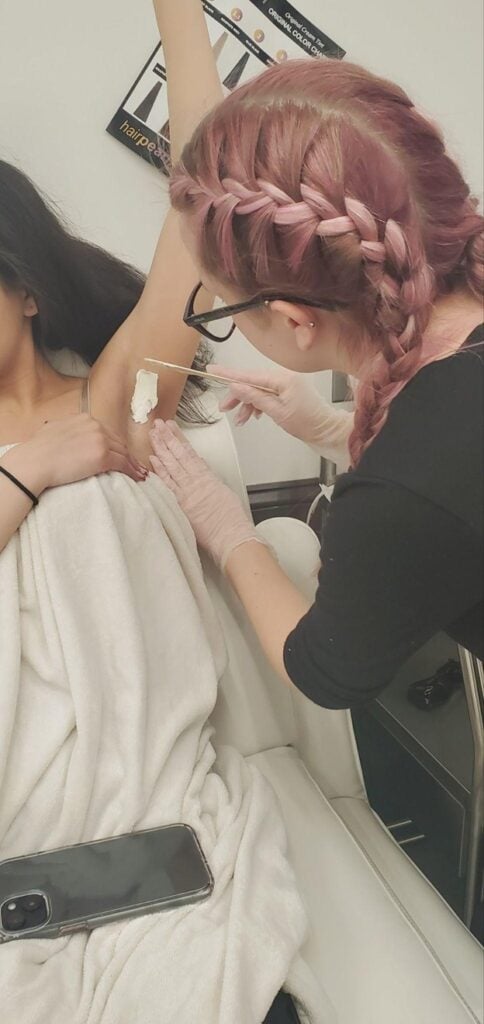 Esthetics student practicing underarm waxing technique under instructor supervision at Cosmetology & Spa Academy.
