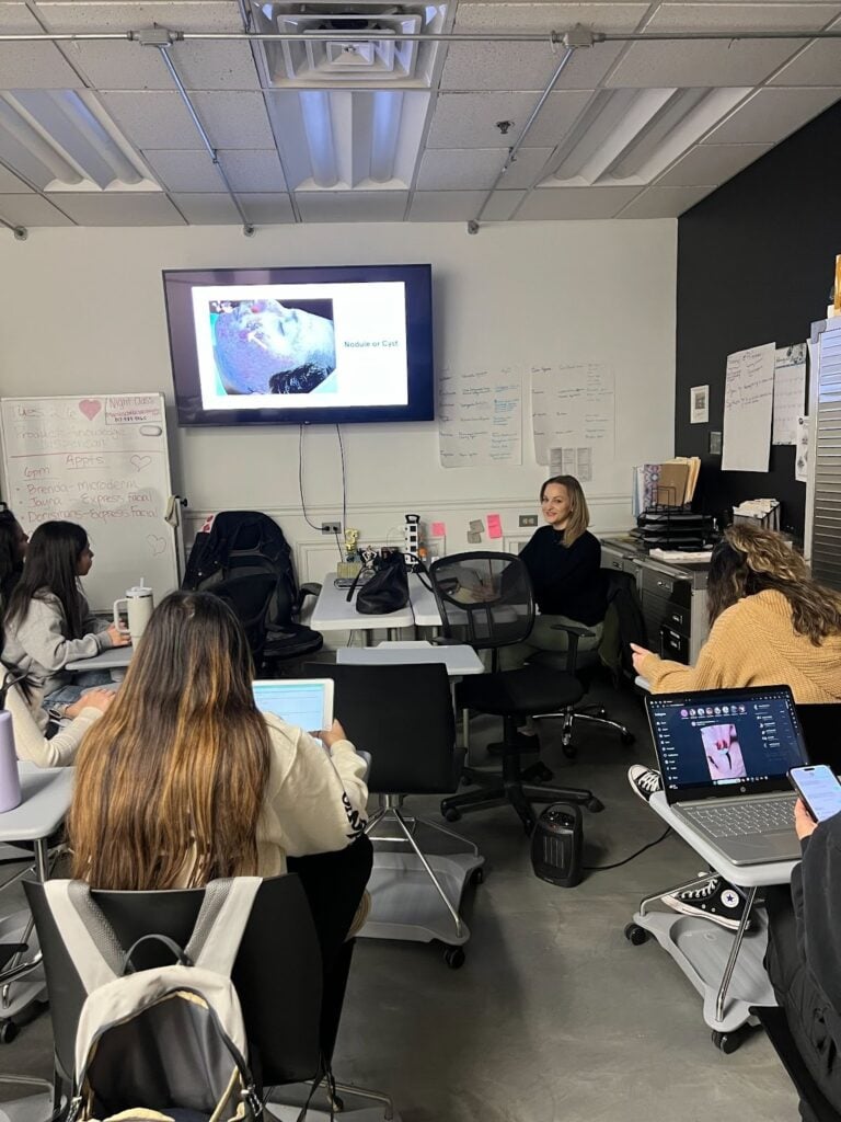 Advanced Facial Treatments Every Esthetician Should Master 5 Students engaged in a classroom presentation.