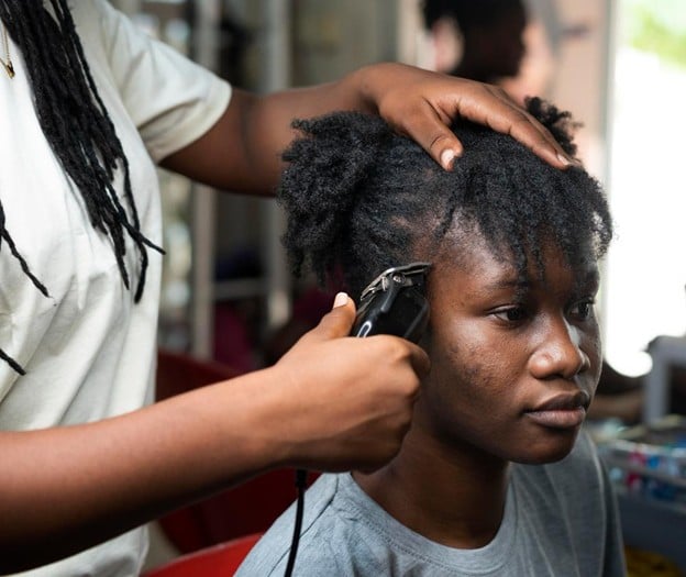 Top Summer Hairstyles - What Clients Actually Keep Asking For in 2026 2 student practicing African hair cutting techniques at Cosmetology & Spa Academy, one of the best hair schools in Illinois